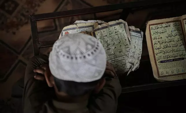 An Afghan boy rests his head on his desk as he dozes off during a Quran class at the Abdullah Ibn-Masoud religious school on the outskirts of Kabul, Afghanistan, Monday, May 26, 2025. (AP Photo/Ebrahim Noroozi)