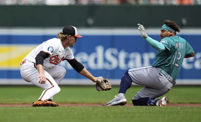Baltimore Orioles shortstop Gunnar Henderson, left, tags out Seattle Mariners' Josh Naylor (12) at second base trying to stretch a single into a double during the first inning of a baseball game, Thursday, Aug. 14, 2025, in Baltimore. (AP Photo/Stephanie Scarbrough)