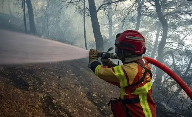 This photo, provided by the Securite Civile on Thursday Aug. 7, 2025, shows a fireman trying to pull off the wildfire near Saint-Laurent-de-la-Cabrerisse, southern France, Wednesday, Aug. 6, 2025. (Securite Civile via AP)