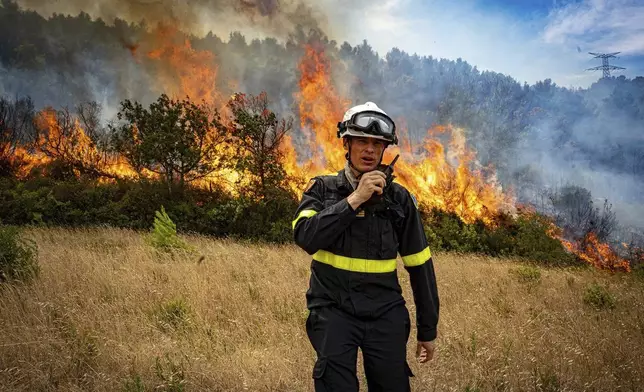 This photo, provided by the Securite Civile on Thursday Aug. 7, 2025, shows a rescuer from the Securite Civile next the wildfire near Saint-Laurent-de-la-Cabrerisse, southern France, Wednesday, Aug. 6, 2025. (Securite Civile via AP)