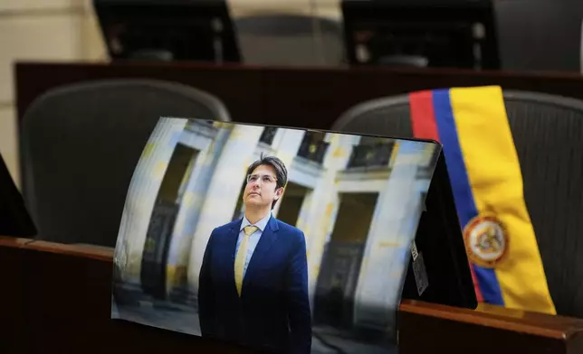 A photo of opposition Sen. and presidential hopeful Miguel Uribe is placed at his seat in Congress in Bogota, Colombia, Monday, Aug. 11, 2025, after his death more than two months after being shot during a political rally. (AP Photo/Fernando Vergara)