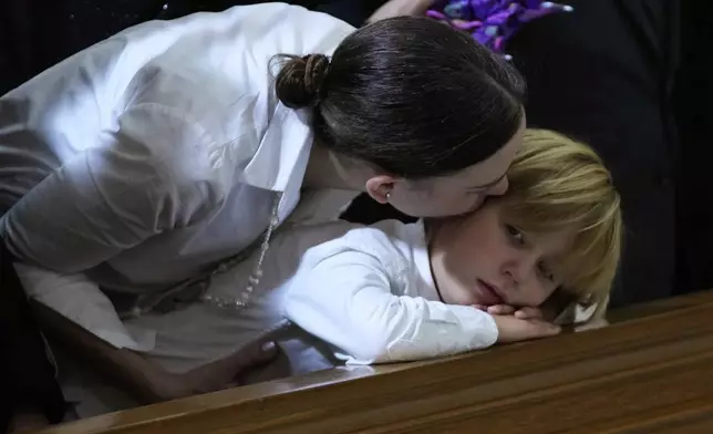Maria Claudia Tarazona kisses her son Alejandro during the funeral service for her husband, presidential hopeful and opposition Sen. Miguel Uribe, who died from wounds suffered when he was shot at a political rally, in Bogota, Colombia, Wednesday, Aug. 13, 2025. (AP Photo/Fernando Vergara)