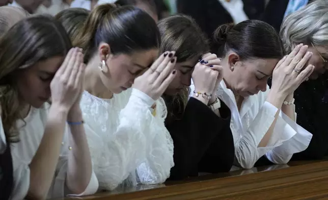 CORRECTS TARAZONA'S MIDDLE NAME - Maria Claudia Tarazona, right, and her three daughters pray during the funeral service for her husband, presidential hopeful and opposition Sen. Miguel Uribe, who died from wounds suffered when he was shot at a political rally, in Bogota, Colombia, Wednesday, Aug. 13, 2025. (AP Photo/Fernando Vergara)