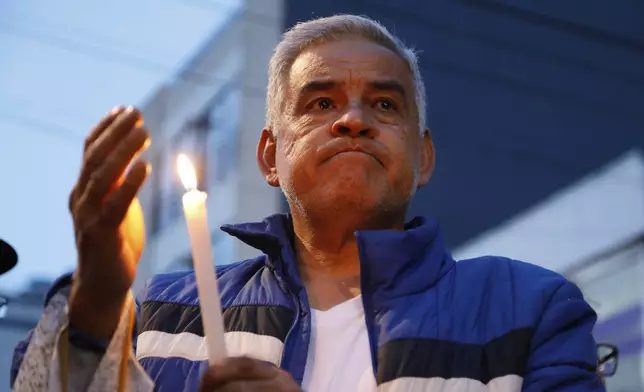 A man holds a candle during a vigil at the site where opposition Sen. and presidential hopeful Miguel Uribe was shot during a political rally, following his death, in Bogota, Colombia, Monday, Aug. 11, 2025. (AP Photo/John Wilson Vizcaino)