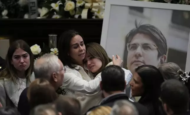 Claudia Tarazona, wife of presidential hopeful and opposition Sen. Miguel Uribe, embraces one of her daughters next to a photo of her husband during a ceremony in his honor at Congress in Bogota, Colombia, Monday, Aug. 11, 2025. Uribe died from wounds suffered after being was shot at a political rally. (AP Photo/Fernando Vergara)