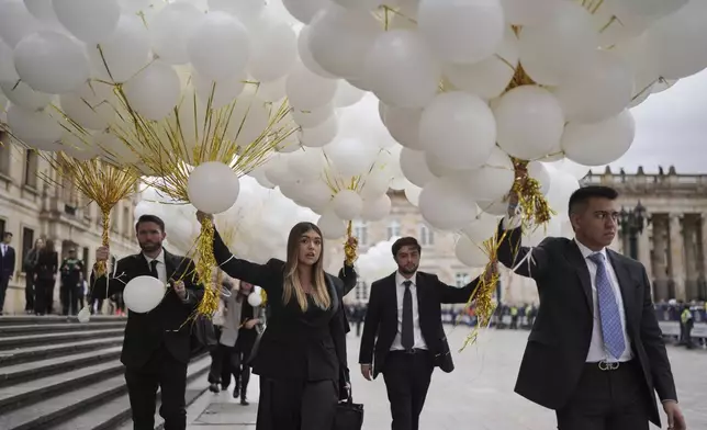 Mourners carry balloons to the Cathedral in Bogota, Colombia, ahead of the funeral Mass for presidential hopeful and opposition Sen. Miguel Uribe, who died of gunshot wounds sustained at a political rally, Wednesday, Aug. 13, 2025. (AP Photo/Ivan Valencia)