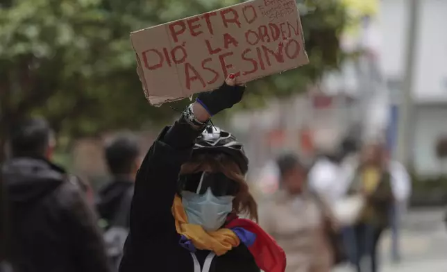 An opponent of President Gustavo Petro holds a sign reading in Spanish, "Petro ordered it. Murderer," outside the clinic where presidential hopeful and opposition Sen. Miguel Uribe died, more than two months after he was shot during a political rally, in Bogota, Colombia, Monday, Aug. 11, 2025. (AP Photo/Ivan Valencia)