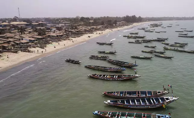 Artisanal fishing boats sit in the water outside the fish landing site in Tanji, Gambia, on March 25, 2025. (AP Photo/Grace Ekpu)