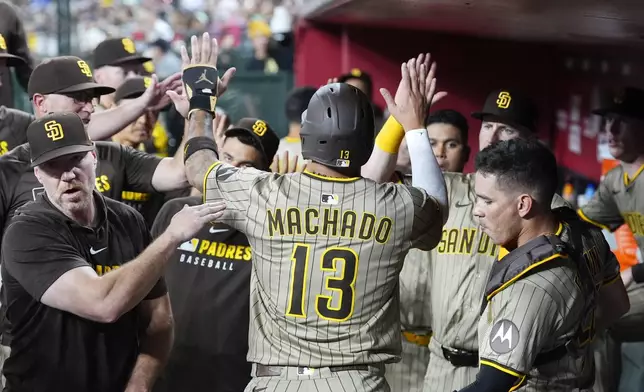 San Diego Padres' Manny Machado (13) celebrates his run scored against the Arizona Diamondbacks with Padres assistant hitting coach Pat O'Sullivan, left, and Padres catcher Freddy Fermin, right, during the third inning of a baseball game Monday, Aug. 4, 2025, in Phoenix. (AP Photo/Ross D. Franklin)