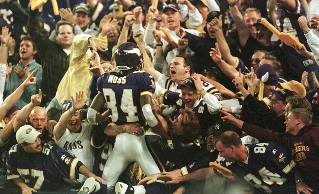 FILE - Minnesota Vikings wide receiver Randy Moss (84) jumps into the crowd to celebrate his 42-yard touchdown pass from Daunte Culpepper during the fourth quarter of an NFL football game against the Tampa Bay Buccaneers, in Minneapolis, Oct. 9, 2000. (AP Photo/Paul Battaglia, File)