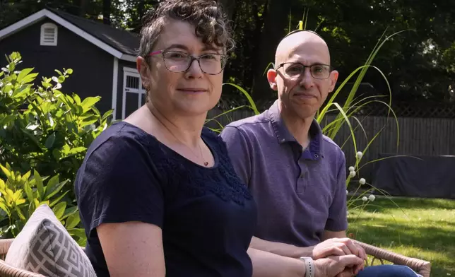 Ziva Mann and her husband Ezra, right, parents of a transgender child and members of a welcoming synagogue, pose in the backyard of their home, Wednesday, Aug. 13, 2025, in Newton, Mass. (AP Photo/Charles Krupa)