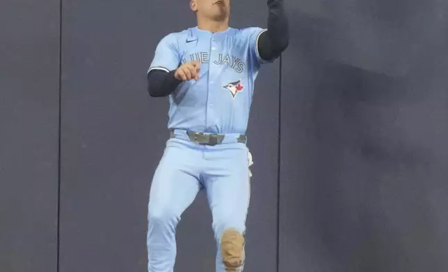 Toronto Blue Jays center fielder Daulton Varsho aims to catch a hit by Miami Marlins' Troy Johnston during the fifth inning of a baseball game, Friday, Aug. 22, 2025, in Miami. (AP Photo/Marta Lavandier)