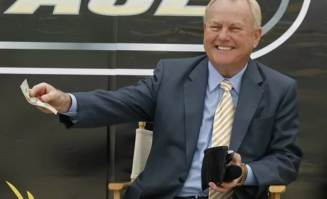 FILE - H.A. "Humpy" Wheeler, president and general manager of Lowe's Motor Speedway, pays up for being late to the news conference to announce the burnout contest that will be held during the pre-race show before the start of the NASCAR Sprint All-Star Race during a new conference at Lowe's Motor Speedway on April 22, in Concord, N.C. (AP Photo/Rick Havner, FILE)