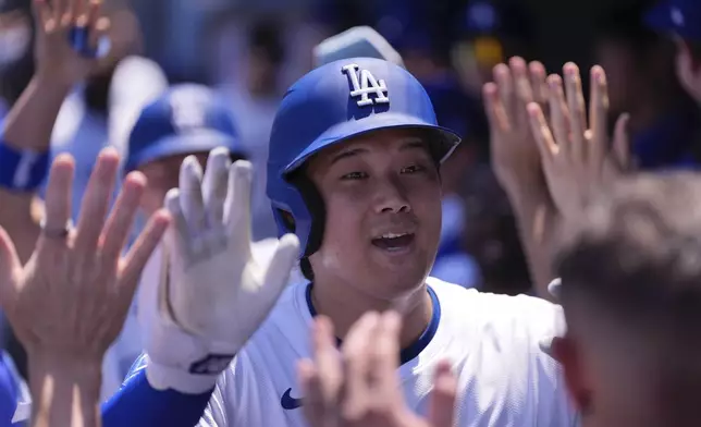 Los Angeles Dodgers' Shohei Ohtani is congratulated by teammates in the dugout after hitting a two-run home run during the third inning of a baseball game against the St. Louis Cardinals, Wednesday, Aug. 6, 2025, in Los Angeles. (AP Photo/Mark J. Terrill)