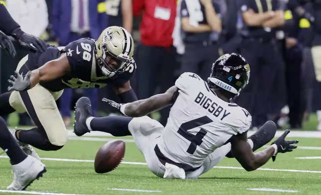 Jacksonville Jaguars running back Tank Bigsby (4) fumbles the ball as New Orleans Saints defensive end Carl Granderson (96) makes the recovery in the first half of an NFL preseason football game in New Orleans, Sunday, Aug. 17, 2025. (AP Photo/Butch Dill)