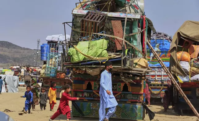 FILE - Afghan refugees children play next to trucks loaded with their family's belonging as they wait to leave for their homeland Afghanistan, at a highway in Landi Kotal, Pakistan, Wednesday, April 9, 2025. (AP Photo/Muhammad Sajjad, File)