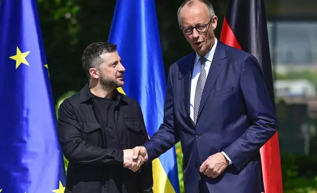 Ukrainian President Volodymyr Zelenskyy, left, is welcomed by German Chancellor Friedrich Merz upon arrival in the garden of the chancellery in Berlin, Germany, Wednesday, Aug. 13, 2025 to join a video conference of European leaders with the US President on the Ukraine war. (John MacDougall/Pool Photo via AP)