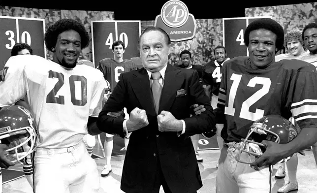 FILE - Comedian Bob Hope is pictured at a taping session Monday, Dec. 10, 1979, in NBC's Burbank Studios with members of the Associated Press All-America football team. With Hope are: Billy Sims of Oklahoma, left, and Charles White of USC, Heisman Trophy winner. Sims won the Heisman Trophy in 1978. (AP Photo/Wally Fong, File)
