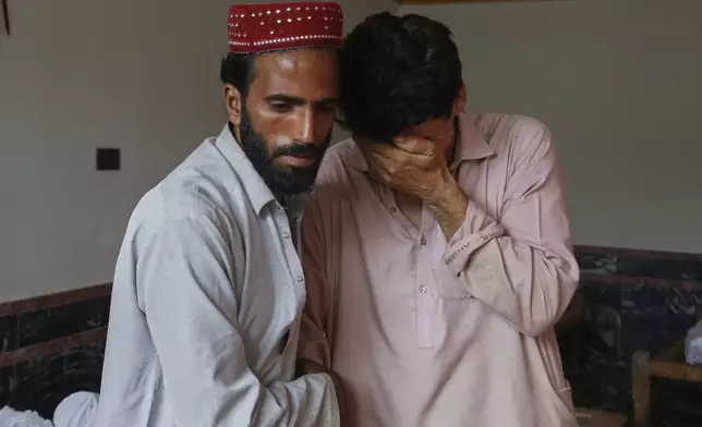 Two men comfort each other as they mourn over the death of their family member in Friday's flash flooding, at a village near Pir Baba, Buner district, in Pakistan's northwest, Saturday, Aug.16, 2025. (AP Photo/Muhammad Sajjad)