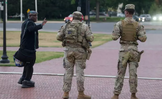 Armed members of the South Carolina National Guard talk with a man while positioned outside of Union Station in Washington, Sunday, Aug. 24, 2025. (AP Photo/Rod Lamkey, Jr.)
