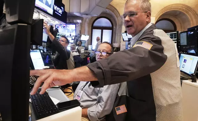 Traders Bryan Masseria, center, and Columb Lytle, right, works on the floor of the New York Stock Exchange, Monday, Aug. 18, 2025. (AP Photo/Richard Drew)