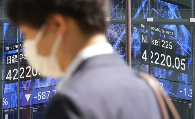 A person walks in front of an electronic stock board showing Japan's Nikkei index at a securities firm Tuesday, Aug. 26, 2025, in Tokyo. (AP Photo/Eugene Hoshiko)
