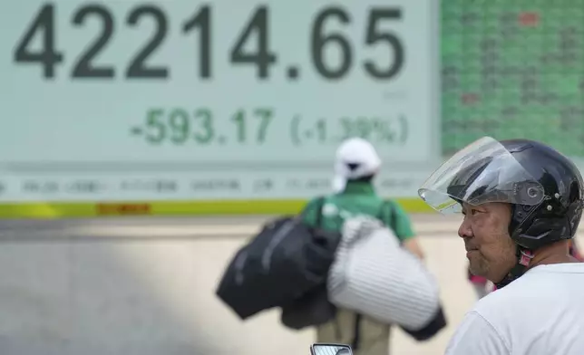 A person pauses in front of an electronic stock board showing Japan's Nikkei index at a securities firm Tuesday, Aug. 26, 2025, in Tokyo. (AP Photo/Eugene Hoshiko)