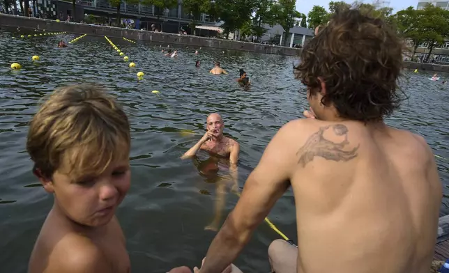 A smoker swims near the Maritime Museum during hot weather in Amsterdam, Netherlands, Wednesday, Aug. 13, 2025. (AP Photo/Peter Dejong)
