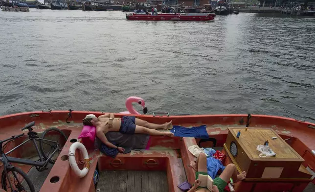 People cool down by the water during hot weather in Amsterdam, Netherlands, Wednesday, Aug. 13, 2025. (AP Photo/Peter Dejong)