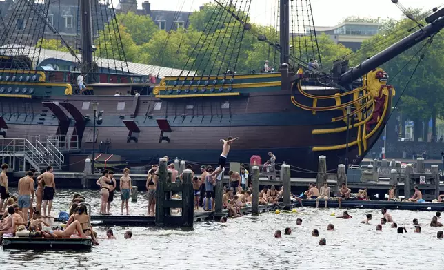 People cool down in the water during hot weather near the Maritime Museum in Amsterdam, Netherlands, Wednesday, Aug. 13, 2025. (AP Photo/Peter Dejong)