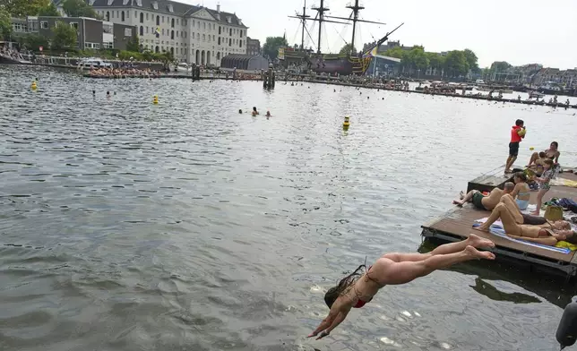 People swim near the Maritime Museum during hot weather in Amsterdam, Netherlands, Wednesday, Aug. 13, 2025. (AP Photo/Peter Dejong)
