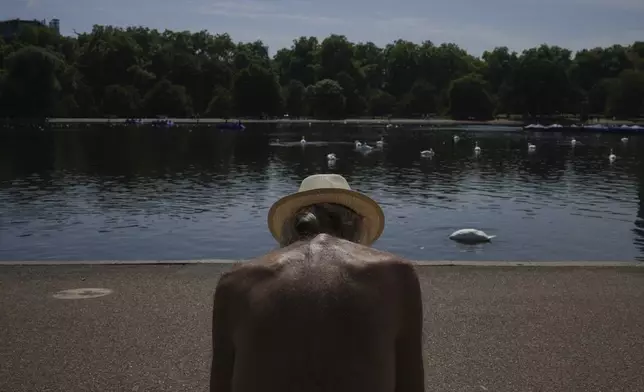 A man sits in the sun at a park in London as parts of the United Kingdom face a heat wave Monday, Aug. 11, 2025. (AP Photo/Kin Cheung)