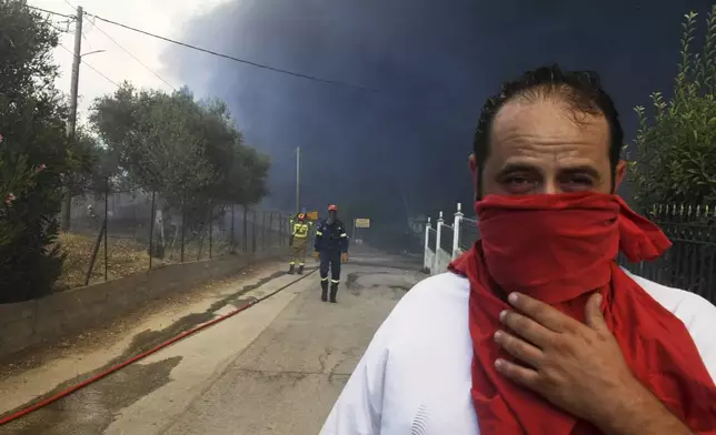 Black smoke covers the sky during a wildfire in the village of Moiraiika near Patras city, western Greece, Tuesday, Aug. 12, 2025. (AP Photo/Giannis Androutsopoulos)