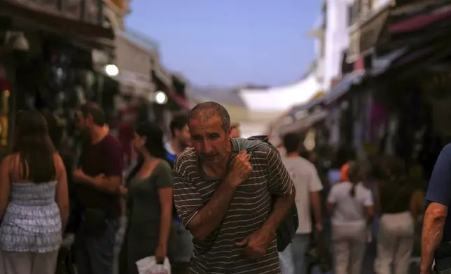 A man carries goods on his back at Eminonu district during a hot summer day in Istanbul, Turkey, Tuesday, Aug. 12, 2025. (AP Photo/Francisco Seco)