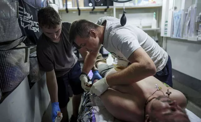 A Ukrainian military medic of 59th brigade treats his injured comrade at a stabilisation point not far from the frontline on Pokrovsk direction, Ukraine, on Friday, Aug. 8, 2025. (AP Photo/Evgeniy Maloletka)