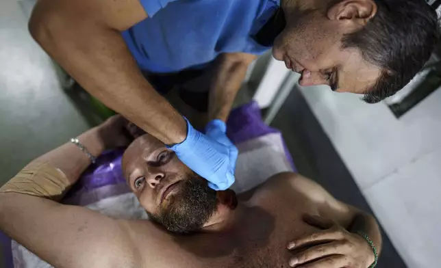 A Ukrainian military medic of 59th brigade treats his injured comrade at a stabilisation point not far from the frontline on Pokrovsk direction, Ukraine, Saturday, Aug. 9, 2025. (AP Photo/Evgeniy Maloletka)