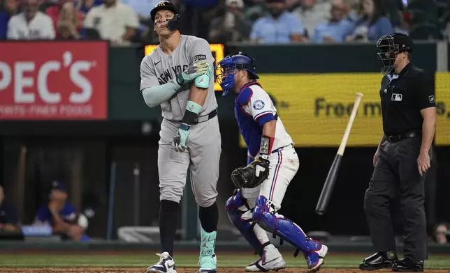 New York Yankees' Aaron Judge tosses his bat after earning a walk as Texas Rangers catcher Kyle Higashioka (11) and umpire Brennan Miller, right, look on in the fifth inning of a baseball game Wednesday, Aug. 6, 2025, in Arlington, Texas. (AP Photo/Tony Gutierrez)