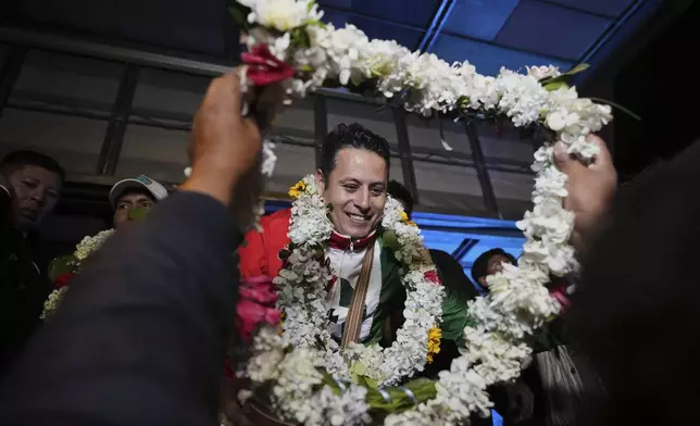 A supporter gifts vice-presidential candidate Edman Lara a flower necklace during a rally a day after he and his running mate Rodrigo Paz won a plurality in the first round of the presidential election, in El Alto, Bolivia, Monday, Aug. 18, 2025. (AP Photo/Natacha Pisarenko)