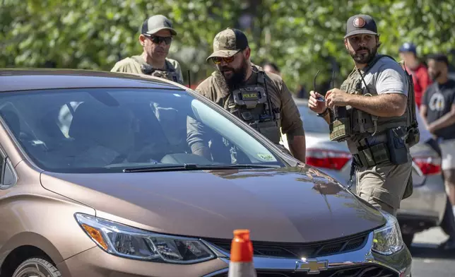 Federal agents talk to a driver at a checkpoint operated by the Metropolitan Police Department and federal agencies, including officers from Immigration and Customs Enforcement (ICE) and Homeland Security Investigations (HSI), on Georgia Avenue in the northern part of Washington, Saturday, Aug. 30, 2025. (AP Photo/Mark Schiefelbein)