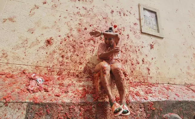 Revelers throw tomatoes at each other during the annual "Tomatina" tomato fight fiesta, in the village of Bunol near Valencia, Spain, Wednesday, Aug. 27, 2025. (AP Photo/Alberto Saiz)