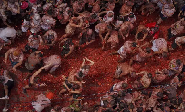 Revelers throw tomatoes at each other during the annual "Tomatina" tomato fight fiesta, in the village of Bunol near Valencia, Spain, Wednesday, Aug. 27, 2025. (AP Photo/Alberto Saiz)