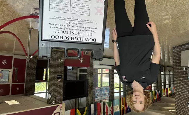 Doss High School Principal Julie Chancellor stands by a new cell phone policy sign at the entrance to the school on Friday, Aug. 15, 2025, in Louisville, Ky. (AP Photo/Dylan Lovan)
