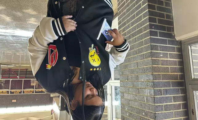 Doss High School student Mia Rivera demonstrates how she puts her phone away before the start of school on Friday, Aug. 15, 2025, in Louisville, Ky. (AP Photo/Dylan Lovan)