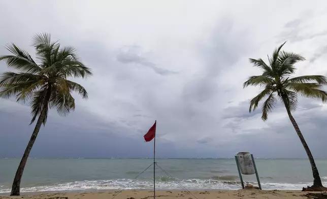 A red flag warns of dangerous waves on an empty beach in San Juan, Puerto Rico, after Hurricane Erin passed by near the island on Sunday, Aug. 17, 2025. (AP Photo/Alejandro Granadillo)