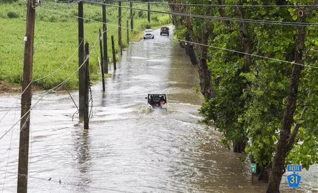 Vehicles traverse a flooded road in Naguabo, Puerto Rico, as Hurricane Erin brings heavy rain to the island, Sunday, Aug. 17, 2025. (AP Photo/Alejandro Granadillo)