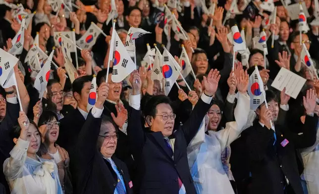 South Korean President Lee Jae Myung, center, waves the national flag and cheers during the 80th anniversary of Korea's liberation from Japanese colonial rule in Seoul, South Korea, Friday, Aug. 15, 2025. (AP Photo/Ahn Young-joon, Pool)
