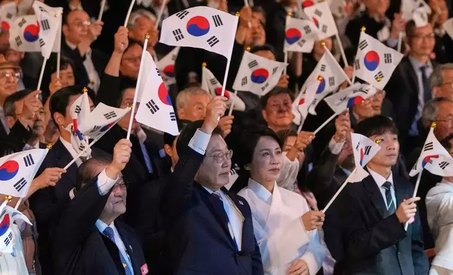 South Korean President Lee Jae Myung, center left, and his wife Kim Hea Kyung, center right, wave the national flags during the 80th anniversary of Korea's liberation from Japanese colonial rule in Seoul, South Korea, Friday, Aug. 15, 2025. (AP Photo/Ahn Young-joon, Pool)