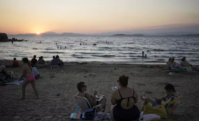 People gather at Kavouri beach as the sun sets in southern Athens, Greece, Monday, Aug. 11, 2025. (AP Photo/Thanassis Stavrakis)