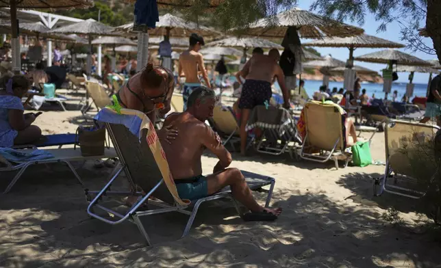 A woman applies sunscreen to a man at Avlaki beach about 42 kilometers (26 miles) east of Athens, Greece, Thursday, Aug. 7, 2025. (AP Photo/Thanassis Stavrakis)