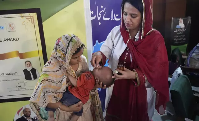 A doctor, right, gives medicine to a child at a relief camp set up for people who fled their homes following torrential rains and rising water level in the Ravi river, on the outskirts of in Lahore, Pakistan, Sunday, Aug. 31, 2025. (AP Photo/K.M. Chaudary)